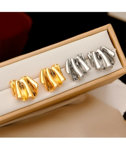Detailed view of geometric crumpled metal earrings in gold and silver within a jewelry box