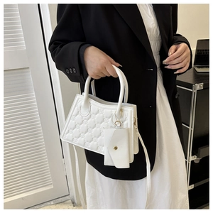 Close-up of white quilted handbag with diamond texture and matching mini envelope charm