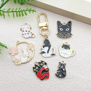 Detail of assorted black and white enamel cat charms with gold trim for DIY jewelry