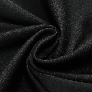 Detail of premium black fabric showing fine texture and elegant draped folds on dress