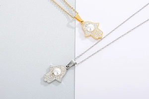 Detailed view of Hamsa Hand pendants in gold and silver with rhinestones and pearl