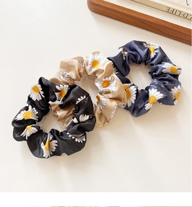 Three-piece set of satin daisy print scrunchies in black, gold, and navy silk textures