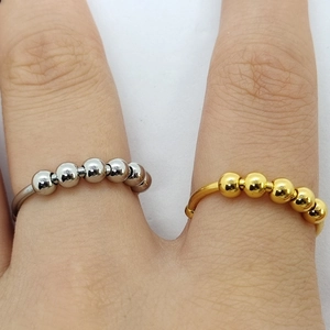 Detalle de anillos antiestrés ajustables en oro y plata con cuentas metálicas giratorias