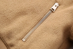 Macro detail of camel plush fabric with high-quality silver metal zipper on a jacket