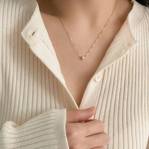 Close-up of a delicate gold heart pendant necklace worn on a model's neck