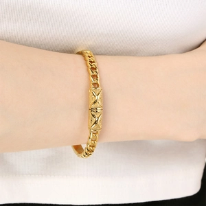Macro shot of gold-plated chunky twist bracelet with embossed X-pattern buckle detail