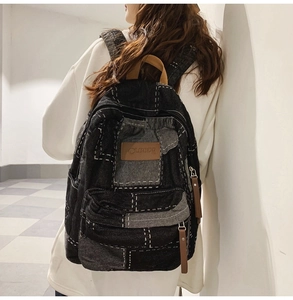 Detail view of vintage patchwork denim backpack with contrast stitching and leather accents