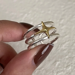 Detail of layered silver ring with a gold star accent held by hand on white backdrop