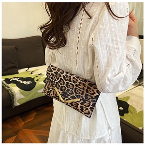 Detailed view of leopard print envelope bag featuring a gold V-shaped metal buckle and chain