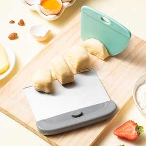 Stainless steel dough scraper and plastic spatula set on wooden board for baking