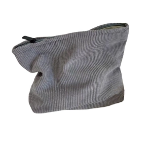 Minimalist grey corduroy pouch with zipper closure and ripple texture on white background