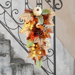 Detail of autumn garland featuring white pumpkins, pine cones, and colorful maple leaves