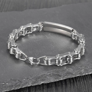 Detailed macro view of silver bicycle chain bracelet with polished metal plate on stone