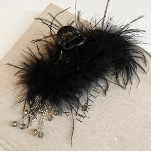 Detail of black acrylic hair claw clip with fluffy feathers and crystal bead tassels