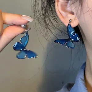 Close-up of blue butterfly tassel earrings showing translucent resin wings and silver hooks