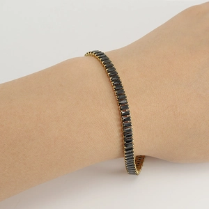 Detailed shot of a gold-plated tennis bracelet featuring black rectangular zircon stones
