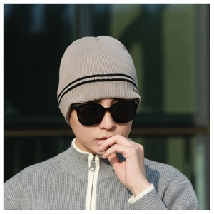 Detail of light coffee knitted beanie featuring vertical stripes and black band decoration