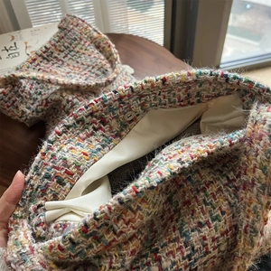 Detail of colorful tweed knit bag showing cream canvas lining and metal magnetic closure
