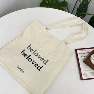 Detail of beloved gradient letter embroidery on beige canvas tote bag with long handles