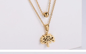 Gros plan du collier doré à deux rangs orné d'un pendentif arbre de vie évidé détaillé