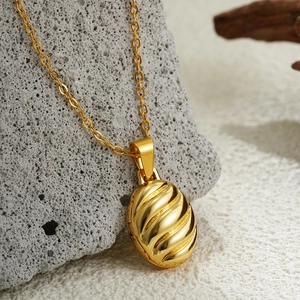 Elegant 18K gold textured oval locket necklace on a rustic grey stone background