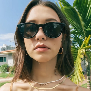 Fashionable black sunglasses with gold necklaces and earrings on a model in sunlight