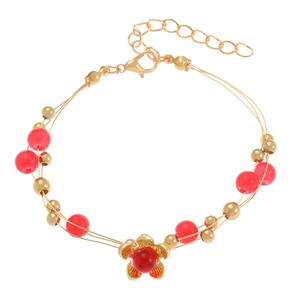 Detalle de pulsera floral dorada con cuentas rojas y cierre de mosquetón ajustable