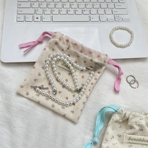 Floral corduroy drawstring pouch with pearl necklace and jewelry set on a desk