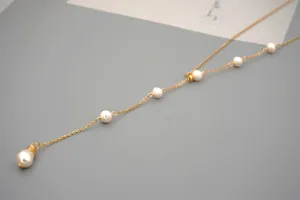 Detail of adjustable gold titanium Y-necklace featuring elegant white freshwater pearls