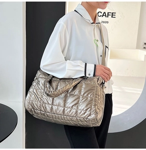 Detailed shoulder view of a silver padded tote bag with diamond quilting on a model