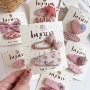 Detail of pink fabric hair clips with bows, stars and pearls on brand cards