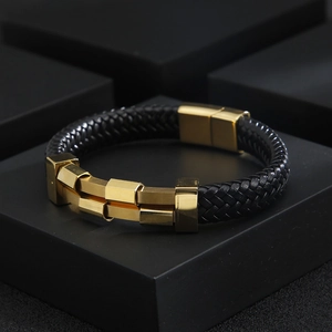 Detail of men's black braided leather bracelet with golden magnetic steel clasp