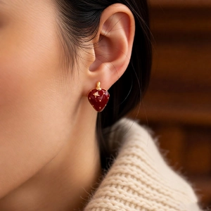 Detailed view of red strawberry stud earrings with gold plating and fine enamel finish