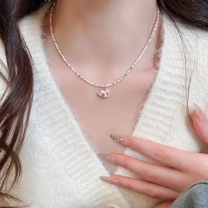 Gros plan d'un collier de perles doux avec un pendentif cheval rose porté au cou