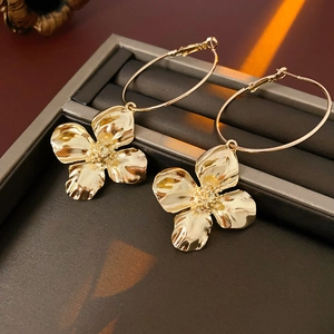 Close-up of golden four-petal flower pendant on hoop earrings in a jewelry box