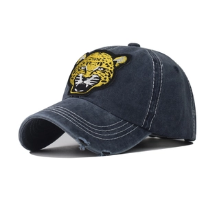 Detail van geborduurde luipaardpatch op vintage gewassen denim baseballpet met versleten rand