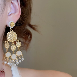Vue détaillée de boucles d'oreilles dorées avec glands en perles et motif mandala
