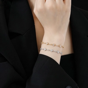 Elegant gold and silver diamond floral bracelets on wrist with black suit background