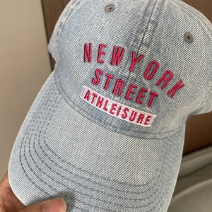 Close-up of light blue denim baseball cap with pink and white New York embroidery