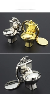 Detail von kreativen Mini-Toilette-Schlüsselanhängern in poliertem Gold- und Silber-Finish