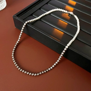 Detail of French style necklace with white pearls and silver metal beads on leather