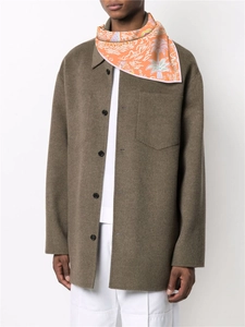 Detail of a square silk scarf with orange tropical palm leaf patterns tied on male model