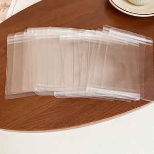 Stack of clear plastic jewelry storage bags on a wooden surface for travel