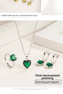 Detail of silver jewelry set featuring heart-shaped emerald green stones on white background