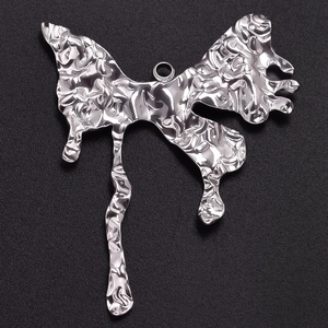 Macro detail of silver liquid metal butterfly pendant with reflective molten texture