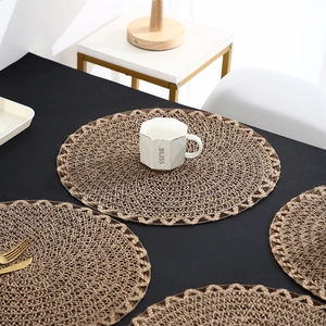 Set of round brown braided placemats on black table with gold cutlery and mug