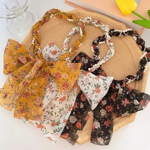 Flat lay of floral chiffon headbands with pearls and chain details in yellow and black