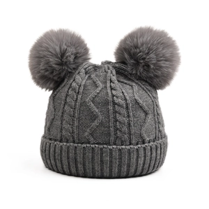 Detail of grey cable knit baby hat featuring thick texture and fluffy double pom-poms