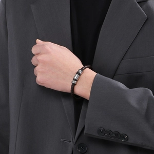 Close-up of brown braided leather bracelet with magnetic clasp on a man wearing a suit