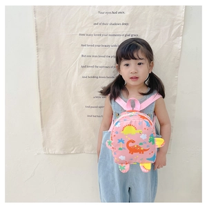 Toddler backpack detail showing pink straps and vibrant cartoon dinosaur prints on nylon